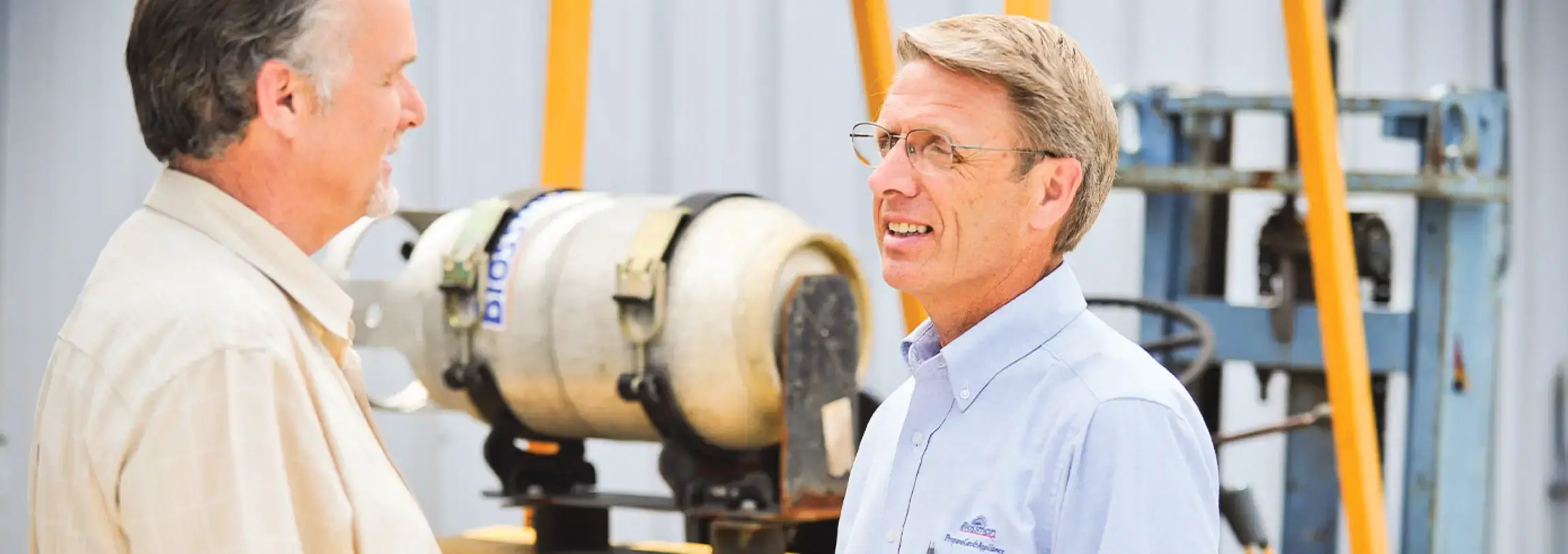 Two men talking by propane cylinder on forklift.